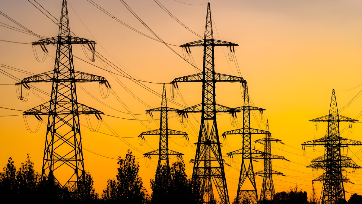 High-voltage transmission towers silhouetted at sunset, representing U.S. grid modernization.