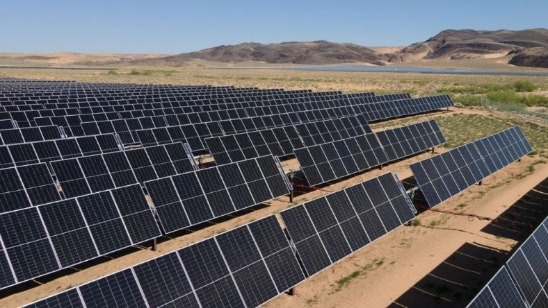 Extensive solar panel arrays positioned in rows across open desert site