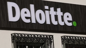 Large Deloitte branded sign mounted on a building facade above decorative iron railings