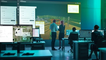 Operators in a control room reviewing a 3D power network on a large display wall