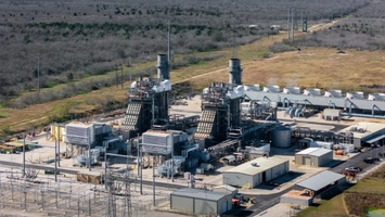 Aerial view of a gas power plant with turbine units, exhaust stacks and transmission lines