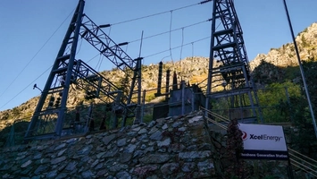 Steel transmission towers and substation above a stone wall at Xcel Energy's Shoshone Generation Station